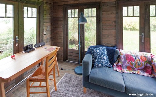 Woodpro Blockhaus Forest BF04 ist im Blockbau konstruiert und hier mit blauen und hölzernen Möbeln versehen